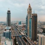 Aerial photograph showcasing Dubai's modern skyline, featuring iconic skyscrapers along a busy highway.